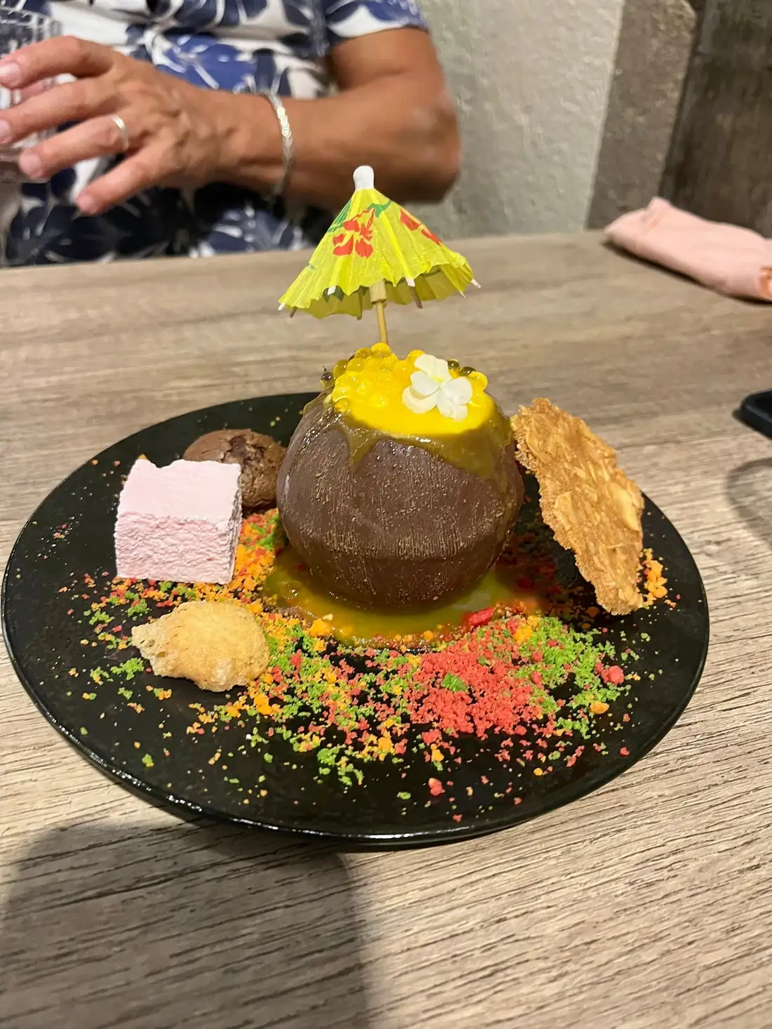 Dessert gourmand à l'ombrelle, guimauve rose et biscuit, sur assiette noire