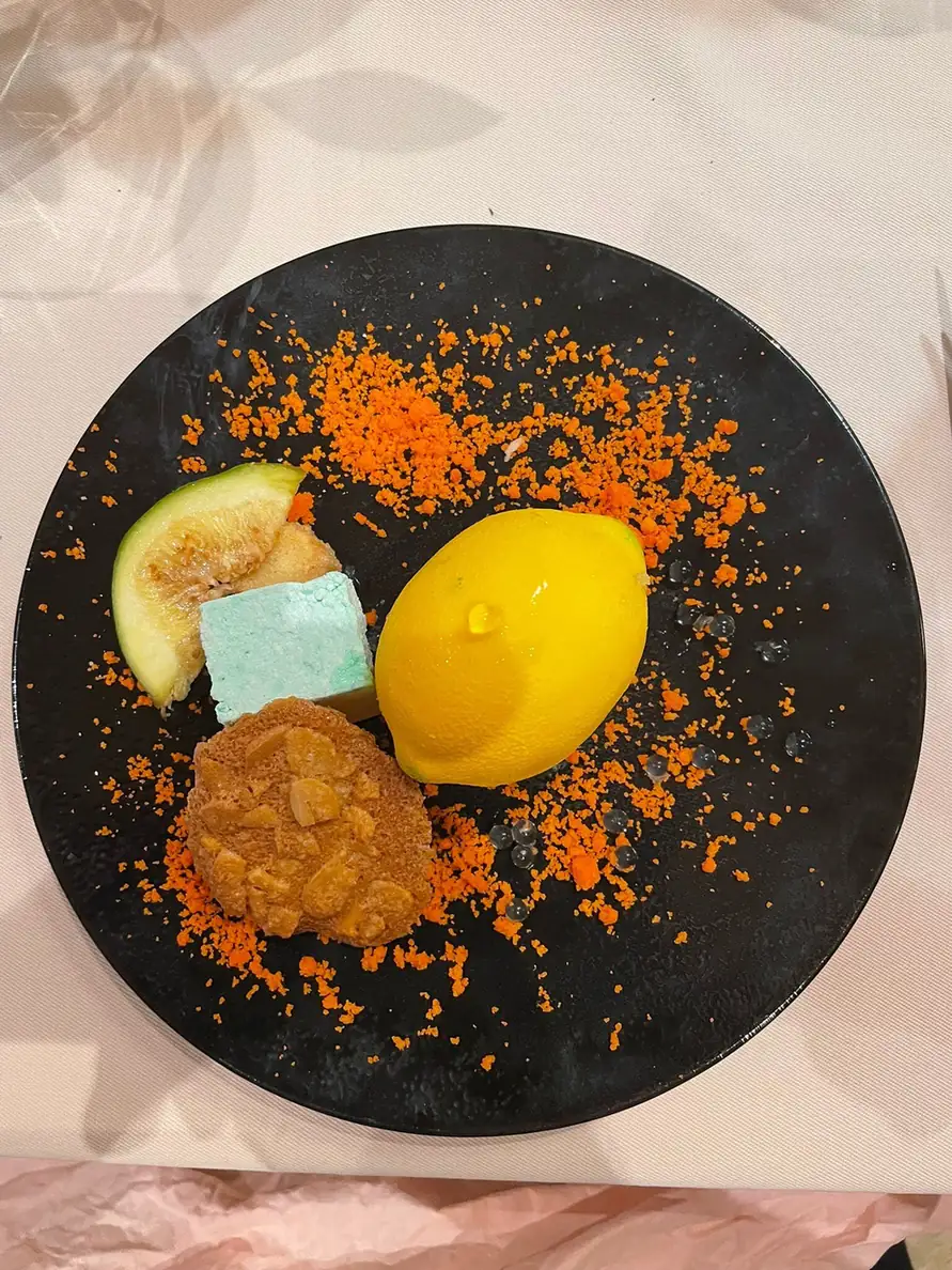 Dessert en forme de citron sur une assiette noire, guimauve et biscuit